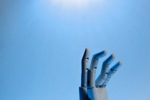 Robotic hand with raised fingers against a bright blue background