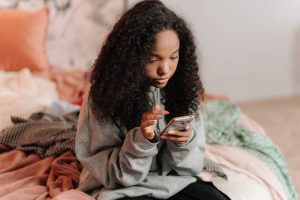 Girl sitting on her bed using her smartphone