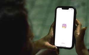 person holding phone displaying an instagram icon