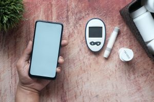 hand holding a phone with a blank screen and some health devices on the desk