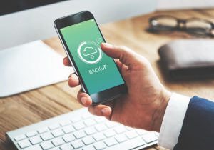 Person holding phone that shows a cloud storage backup icon
