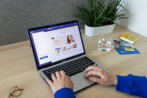Laptop displaying an ecommerce site, a man's hands on the keyboard.