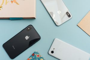 iPhones and Android phones lying face down on a sky blue background
